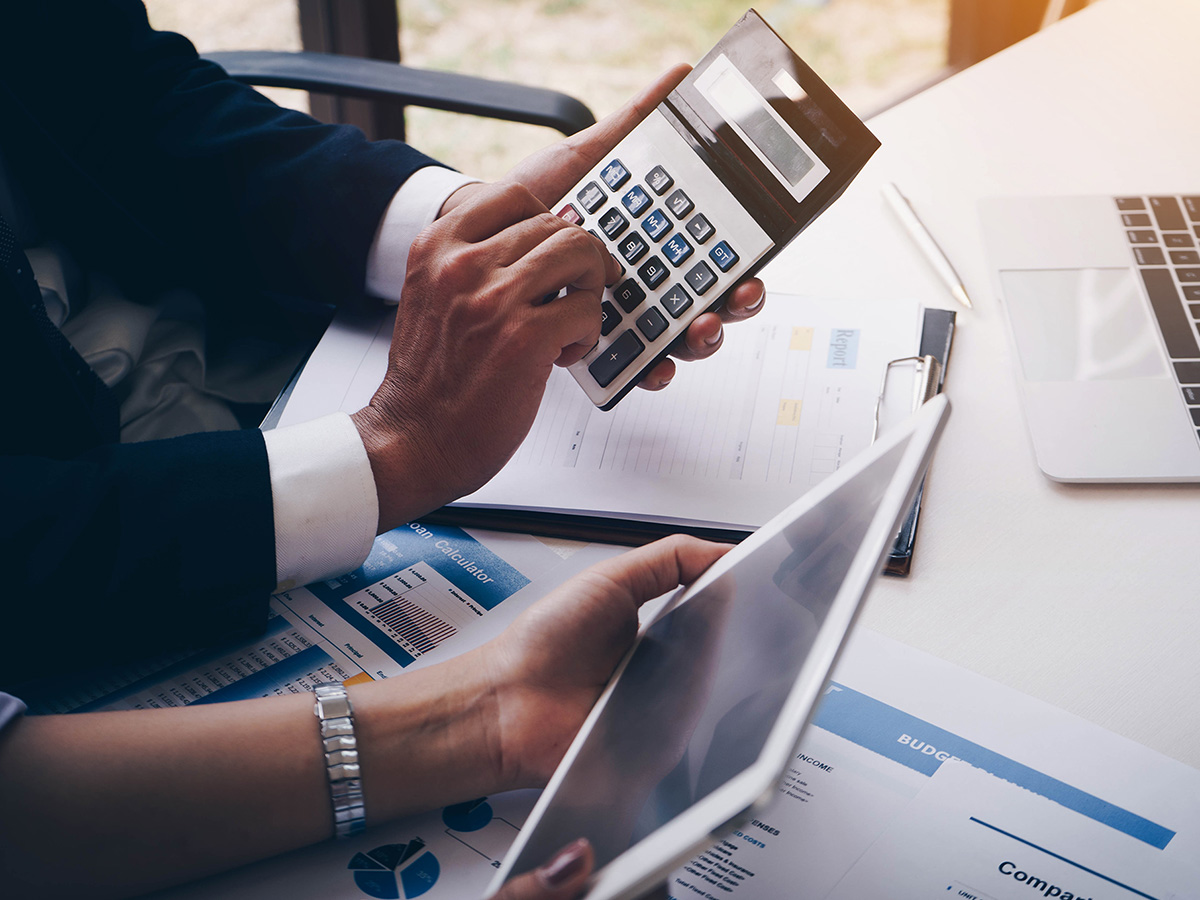 An accountant and business owner's hands while they do taxes